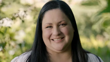 Portrait of Clarissa in a white blouse with blurred trees in the background.