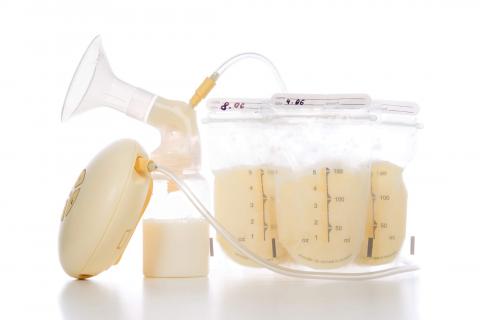 A breast pump connected to a collection bottle and storage bags filled with expressed breast milk for feeding infants.